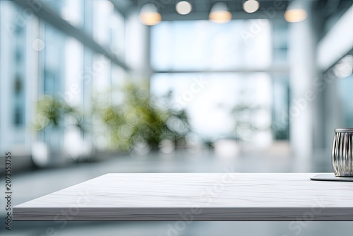 A modern interior scene features a white marble tabletop in the foreground, with a blurred background showcasing a bright, airy office space filled with natural light and greenery.