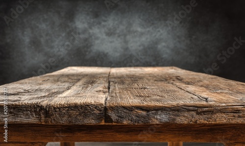A close-up shot showcases a weathered wooden table surface against a textured, dark gray background, creating a rustic and industrial aesthetic.