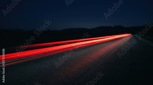 Cinematic long exposure captures vibrant red light trails of a car speeding down a dark country road at night