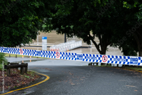 Fotografi Police Tape Blocking Flooded River After Heavy Rain