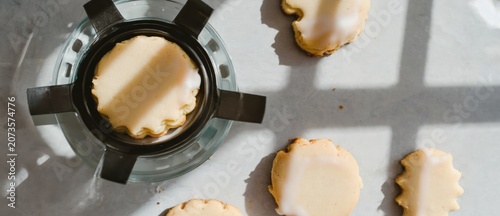 Overhead view of several small round iced cookies and a cooking element