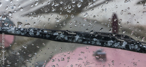 Принти на полотні Black windshield wiper blade of pink vehicle coated with chunks of fallen hail a