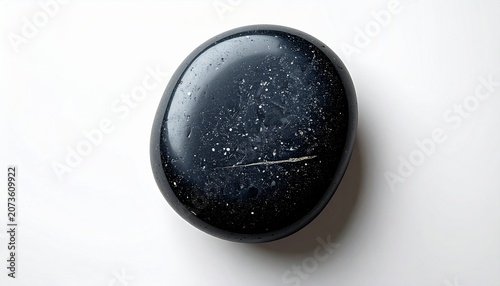 A close-up shot of a black stone with white speckles on a white surface