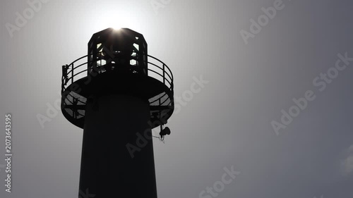 Sun Rising Over Silhouette Of A Lighthouse.