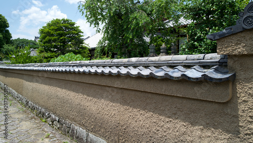 Foto raditional Japanese earthen wall with tiled roof along a stone path in Kyoto