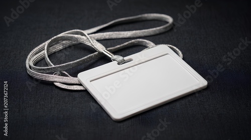 Blank white plastic ID card holder with white lanyard on dark gray background.