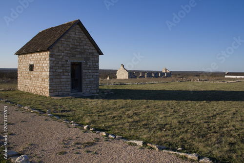 a stone building casting a long shadow of the setting sun