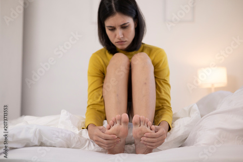 The young woman felt pain in her foot. She touched it and gently massaged it.