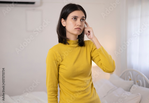 The young woman was deep in thought about something in the bedroom, her posture showing contemplation and worry.