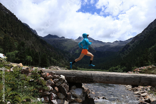 Woman trail runner cross country running in high altitude mountains