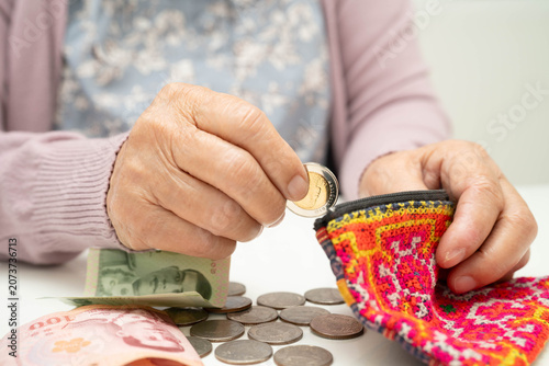 Obraz na płótnie Asian senior or elderly old lady woman holding counting coin money in bag