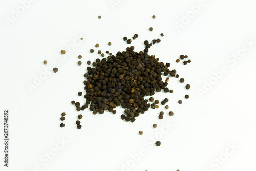 Foto A pile of whole black peppercorns scattered on a white background, isolated on w
