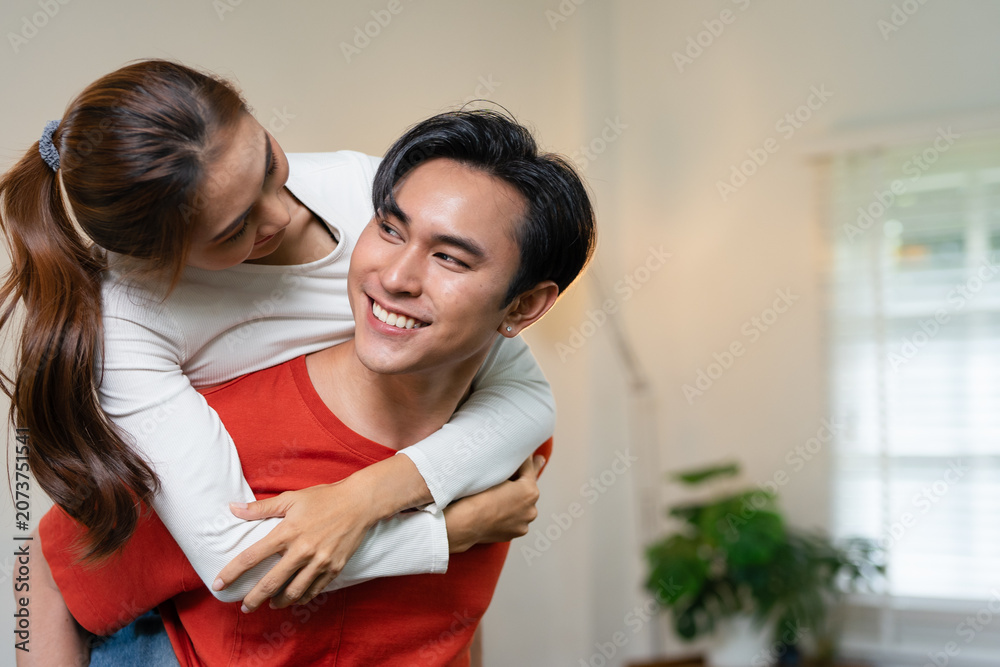 Fototapeta premium Couple, people and smile in home with piggyback to relax for bonding, love and support together.