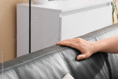 Schilderij op canvas Hand resting on black leather sofa armrest