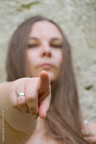 Selective focus portrait with a woman pointing directly at the viewer. Sharp finger and blurred face create a symbolic concept of accusation responsibility attention and choice