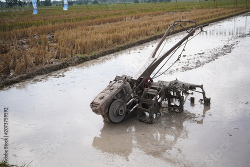 Foto Agricultural power tiller operating on a muddy paddy field.