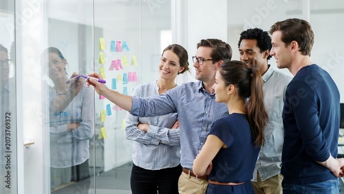 Diverse business team brainstorming on a glass wall in office