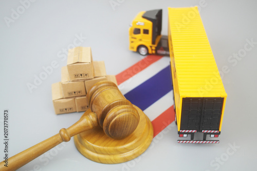Cargo truck and heap of carton boxes with Thai flag and judge gavel on grey background.	