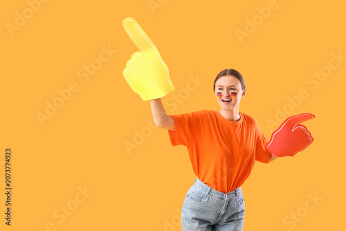 Female German soccer fan with foam hands on yellow background