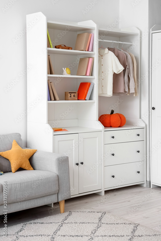 Naklejka premium Closet with childrens clothes, books and toys in room