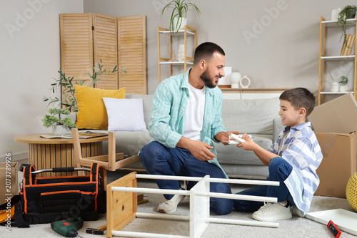 Father with his cute son assembling shelf unit at home