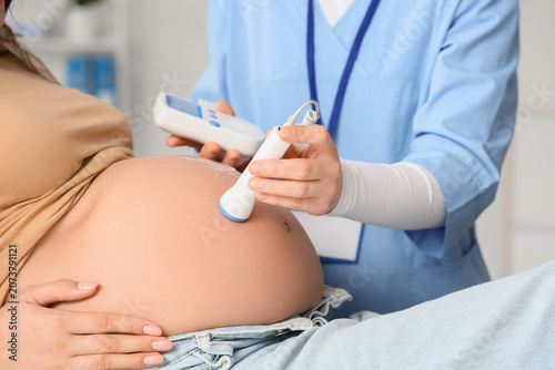 фотографія Young pregnant woman and doctor with fetal doppler listening to babys heartbeat