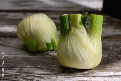 Freshly sliced fennel bulbs showcase vibrant green stalks on rustic wooden table during afternoon light