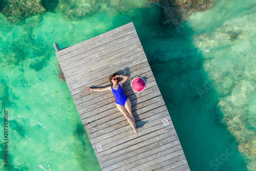 Quadro su tela Aerial view of woman laying on wooden pier at sunny summer day in Cancun, Mexico, top view