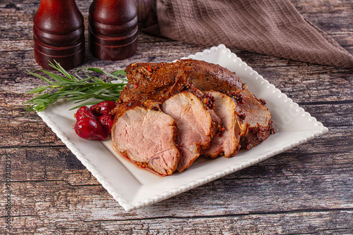 Photos Sliced roasted pork loin with rosemary and red peppers on white plate