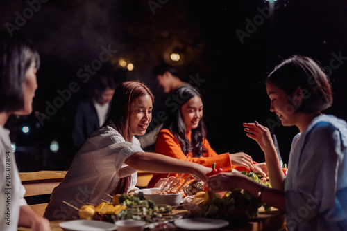 Foto Friends enjoying barbecue dinner gathering at night outside