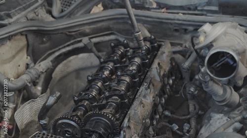 Amidst the rhythmic hum of machinery, a mechanic deftly tightens the camshaft pin on a diesel engine, transforming his workshop into a sanctuary of mechanical mastery.