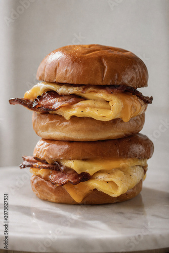 Stacked breakfast sandwiches with melted cheese and crispy bacon between toasted buns