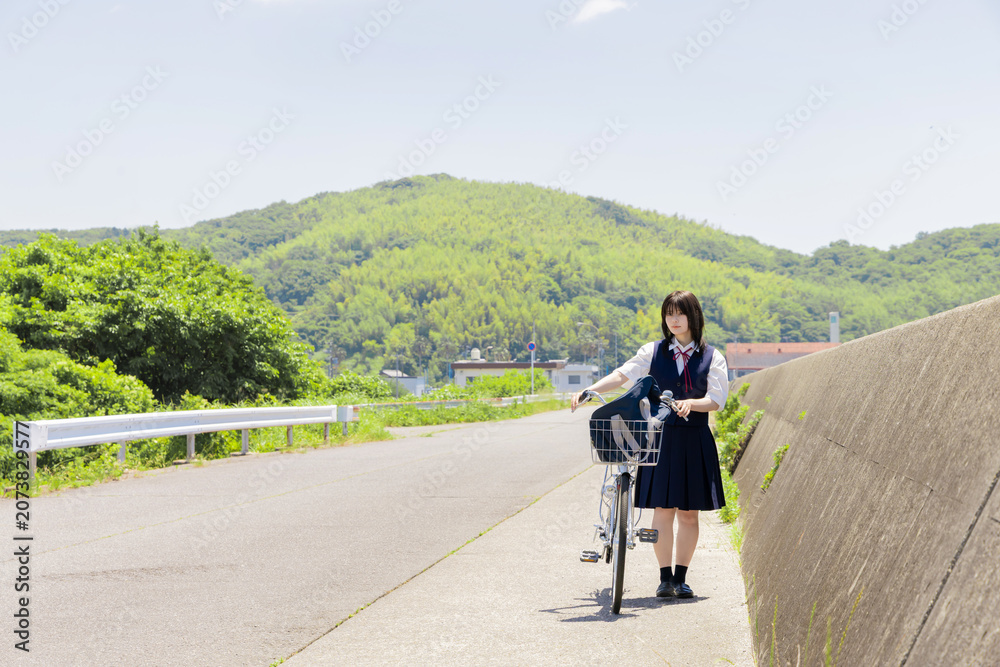 Fototapeta premium 海辺の通学路で自転車を押す女子高校生