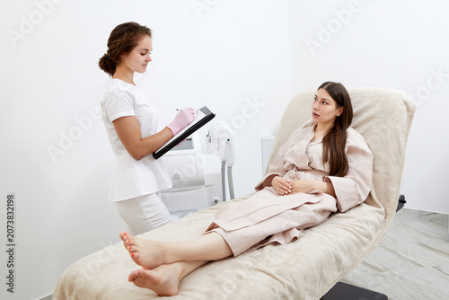Quadro su tela Professional cosmetician woman with papers talking to woman before procedure in