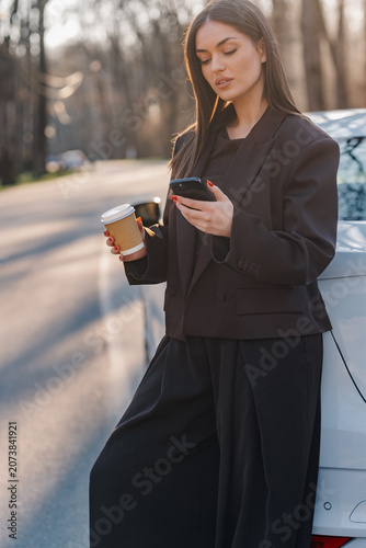Fotografie Woman responding text message drinking coffee outdoor