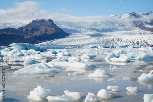 Bild auf Leinwand Vast glacial lagoon filled with floating icebergs in front of a massive glacier