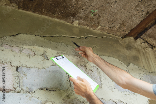Man checking a cracked wall after earthquake.
