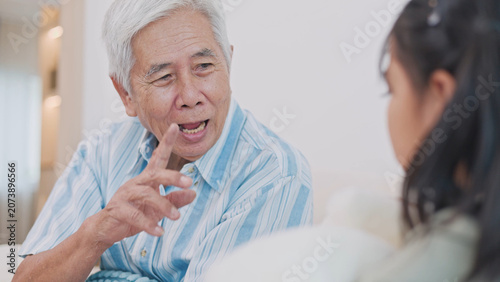 Fotografie Asian grandfather and granddaughter spending time together at home, sharing learning, family love, care, and meaningful intergenerational moments