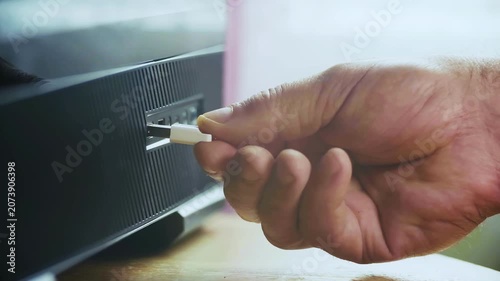 The image shows a hand holding a USB stick inserted into the device.