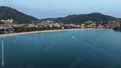 Tableau sur toile Aerial perspective of a tranquil beach with clear blue water, surrounded by green mountains and a small town