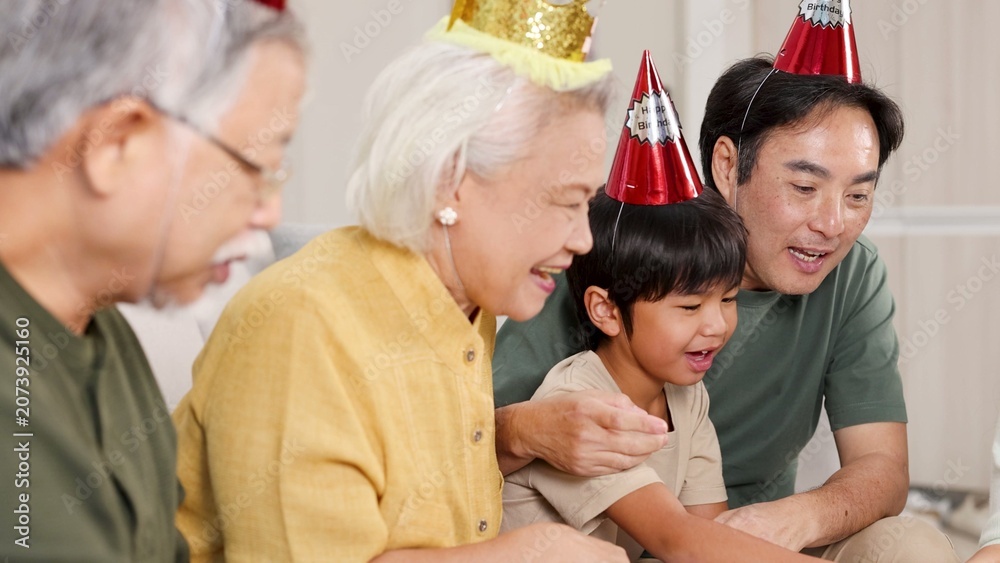 Fototapeta premium Multigenerational Asian Family Wearing Party Hats Celebrating a Birthday Together