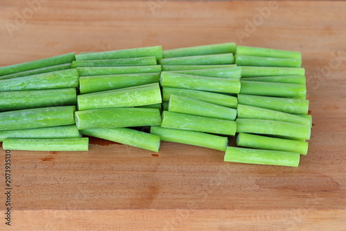Fresh green scallions, chopped into pieces, are laid out on a wooden floor, ready for cooking and preparing healthy meals.