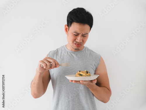 Asian man shows hesitation before sampling food carefully