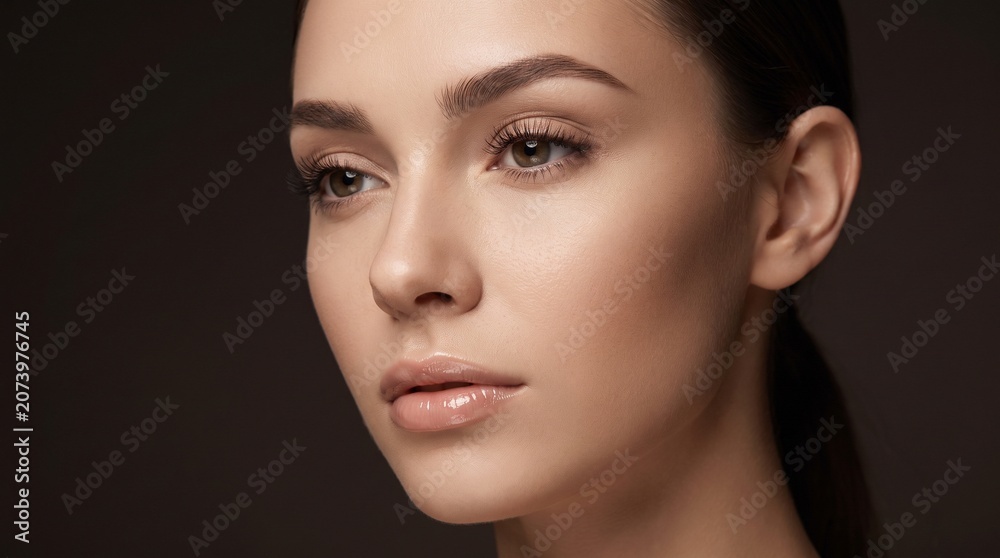 Fototapeta premium Stunning macro beauty portrait of a gorgeous young woman with flawless glowing skin and nude makeup looking away