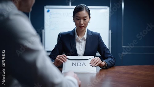 Professional Meeting: A Businesswoman Presents an NDA Document During a Confidential Discussion with a Colleague in a Modern Office Setting