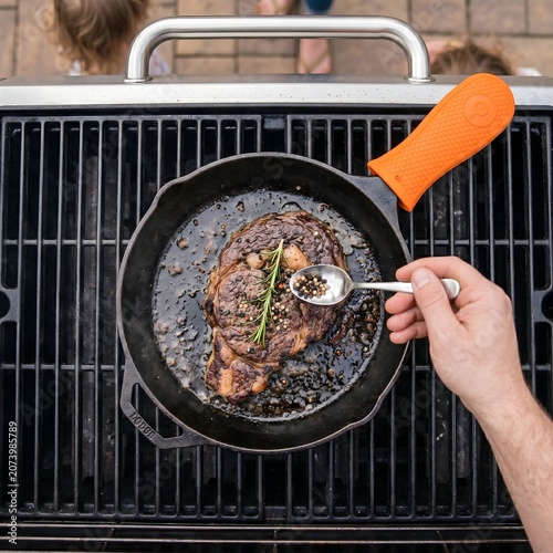 Steak searing in cast iron skillet on outdoor gas grill gourmet cooking