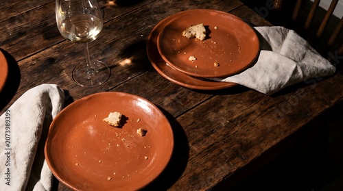 Empty clay plates with food crumbs and wine glass on rustic wooden table after dinner concept
