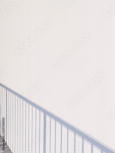 Minimalist background with aesthetic shadow of balcony railing on white concrete wall texture in morning sunlight with copy space