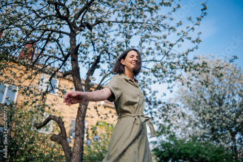 Woman smiling and dancing under a blossoming apple tree in spring