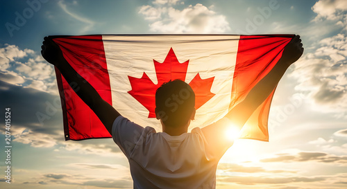 Person Holding Canadian Flag Against Sunset Sky with Silhouette and Sun Flare